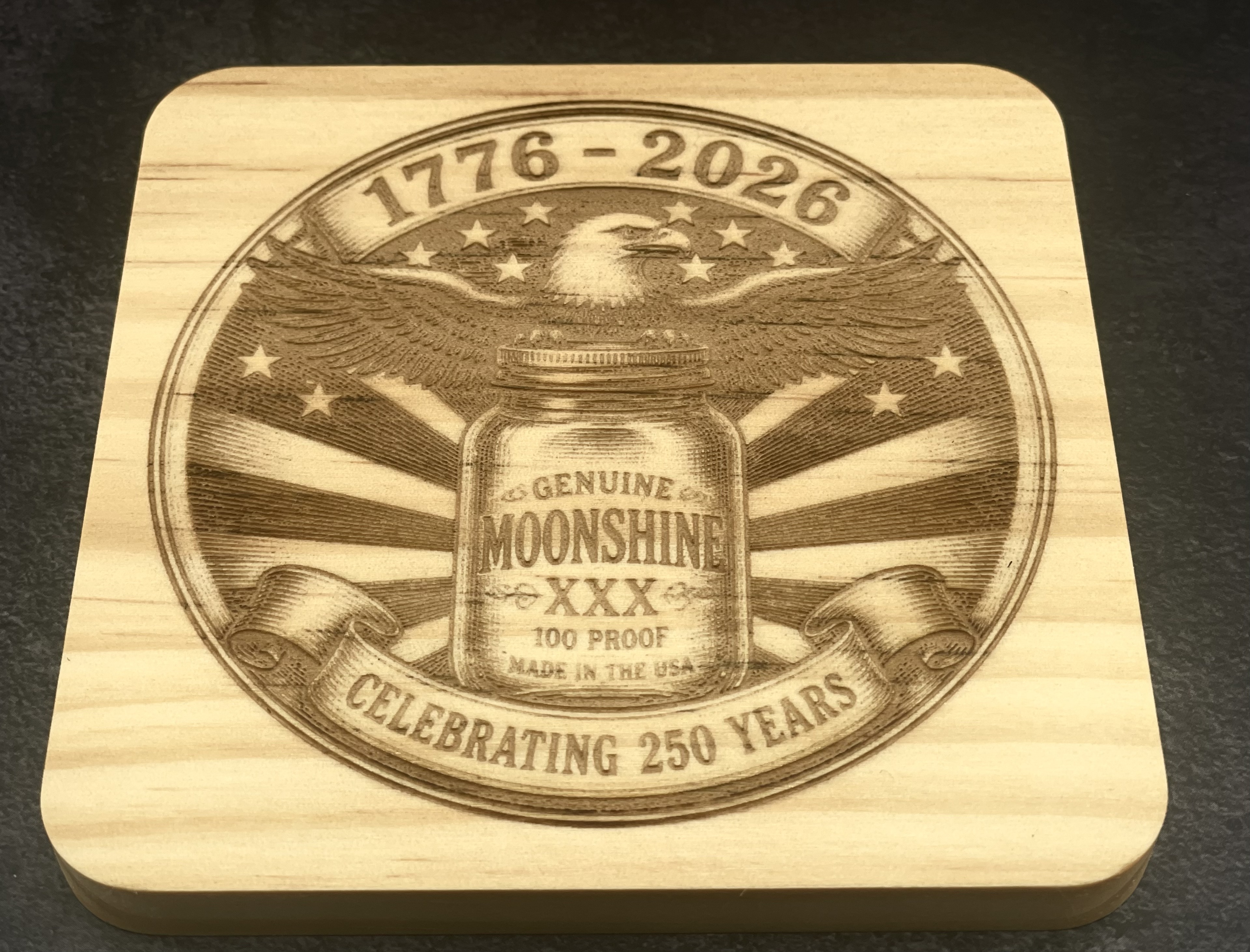 Genuine Moonshine XXX wood coaster with a 1776 to 2026 eagle design, laser engraved