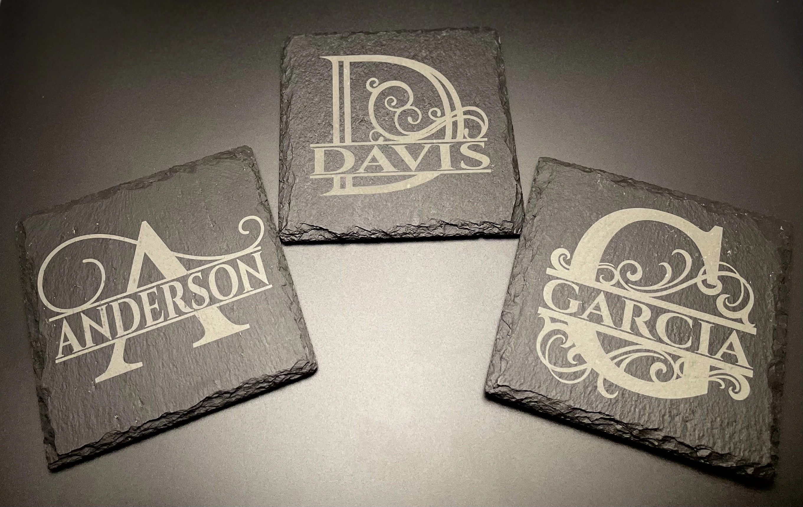 Assorted split-monogram slate coasters laser-engraved with last names